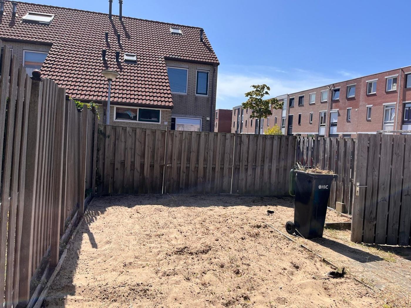 Dezelfde achtertuin na het wieden: kaal en schoon, klaar voor een nieuwe indeling